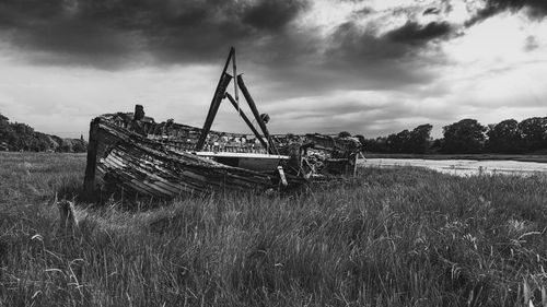 Abandoned ship on field against sky