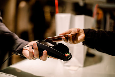 Cropped hand of female customer paying through phone at store