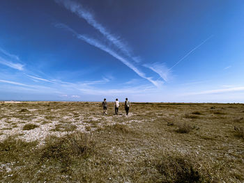 People standing on field against sky