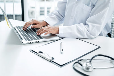 Midsection of man using laptop on table