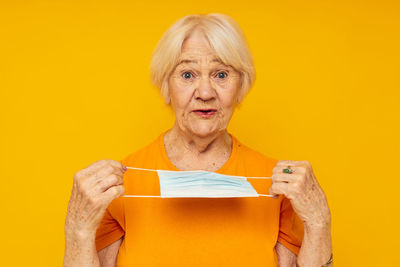 Portrait of woman holding gift against yellow background