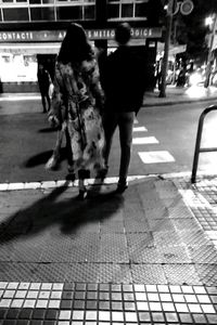 Rear view of people walking on illuminated city at night