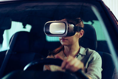 Woman wearing 3d vr goggles, driving car in virtual space