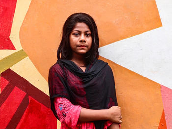 Portrait of girl standing against wall