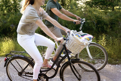 Couple riding bicycle against trees