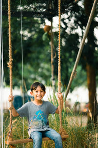 Portrait of smiling boy on swing at playground