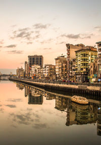 Reflection of cityscape against sky during sunset