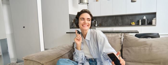 Young woman using mobile phone while sitting on sofa at home