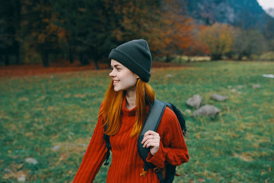 Young woman looking away while standing on field during autumn