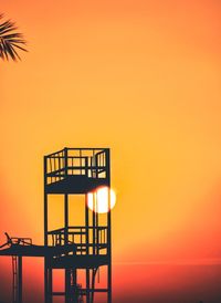 Silhouette railing by sea against sky during sunset