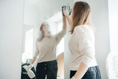 Positive woman cleaning glass at home