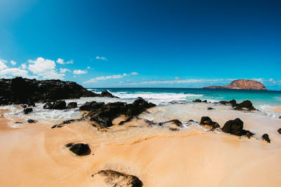 Scenic view of beach against blue sky