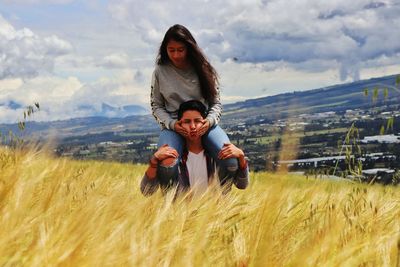 Portrait of smiling young woman sitting on man's shoulder