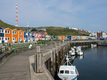 Sailboats moored on river by buildings against sky in city