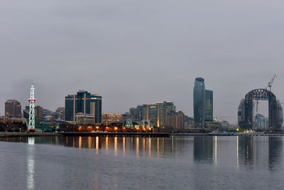 Sea by modern buildings against sky in city