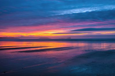 Scenic view of sea against dramatic sky during sunset