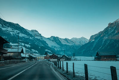 Road amidst snowcapped mountains against clear sky