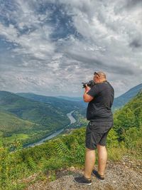 Man photographing on mountain against sky