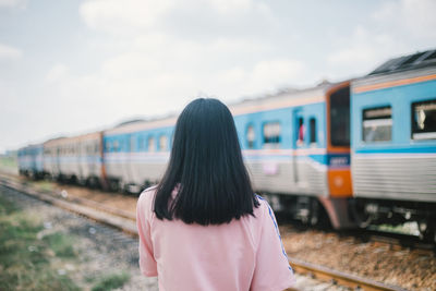 Rear view of woman standing at railroad station