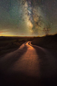 Road amidst landscape against sky at night