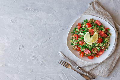 Tabbouleh salad on a dish on light gray concrete background. lebanese cuisine. top view.