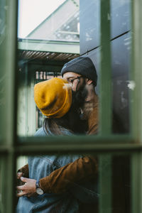 Woman looking at camera while standing by window