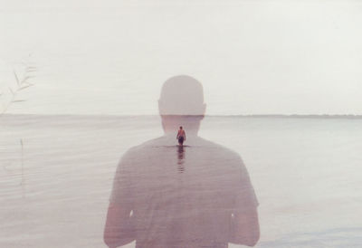 Rear view of man standing on sea shore against sky