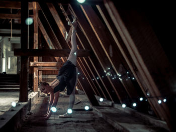 Full length of ballerina practicing by wooden structure