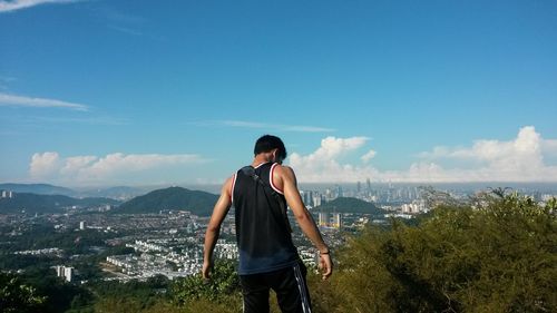 Young man looking at cityscape against sky