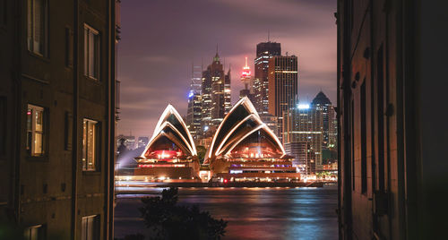 View of illuminated bridge and buildings against sky at night