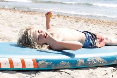 Midsection of woman lying on sand at beach