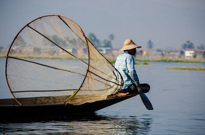 Fisherman with fishing net on boat over lake