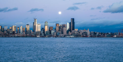 A full moon shines above the seattle skyline.