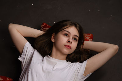 Portrait of young woman sitting against black background