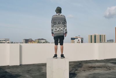 Rear view of woman standing by sea against sky