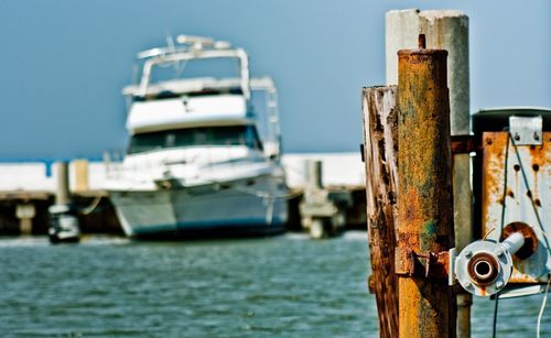 Close-up of wooden post at harbor against sky