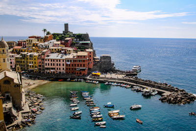 High angle view of boats moored at harbor by town against sky