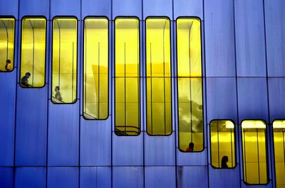 Low angle view of people on escalator seen through yellow windows