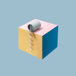 Blue bean can with attached pilot ladder placed on a pink, blue and yellow cube in blue background. 