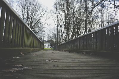 Footbridge amidst trees against sky