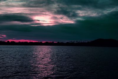 Scenic view of sea against cloudy sky at dusk