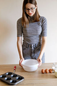 Woman in t-shirt and jeans preparing homemade cupcakes in her kitchen