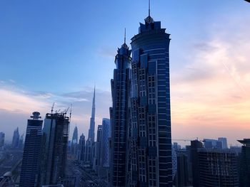 Low angle view of skyscrapers against cloudy sky