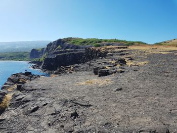 Rock formation on beach against clear blue sky