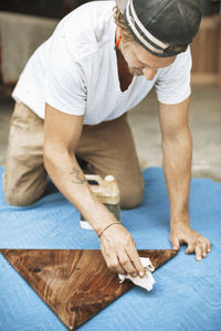 Carpenter polishing triangle shaped wood at workshop