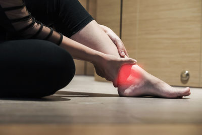 Digital composite image of woman holding foot in pain on floor