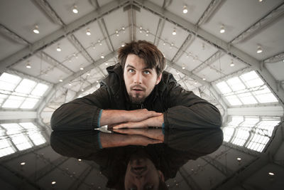 Portrait of young man sitting on ceiling