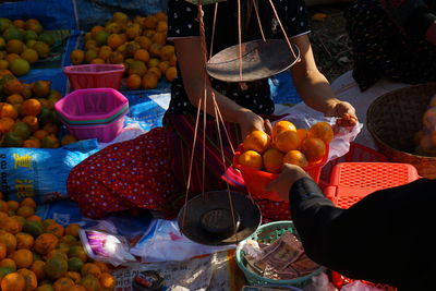 Woman weighing fruits and selling at market stall