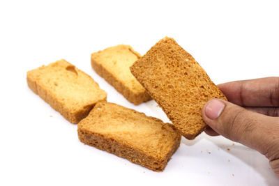 Close-up of hand holding bread against white background