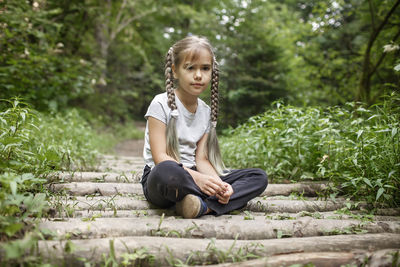 Full length of girl sitting on plants